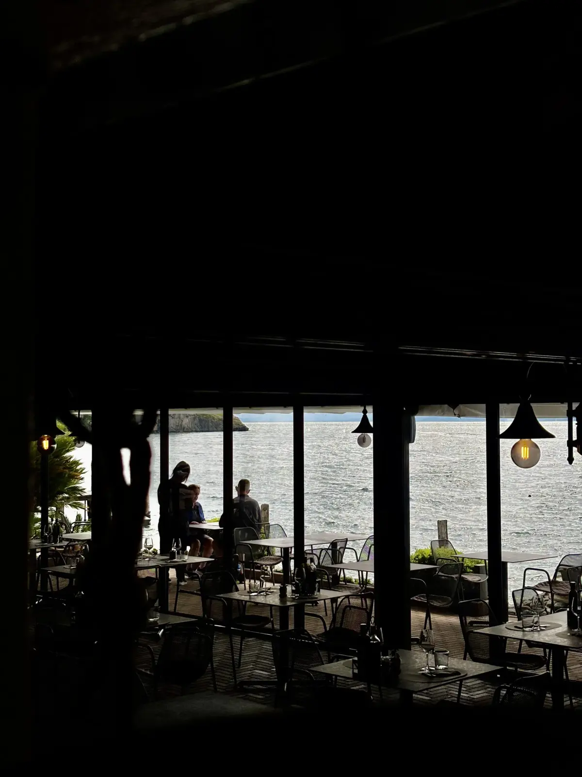 Ospiti seduti ai tavoli in riva al lago visti dall'interno della sala